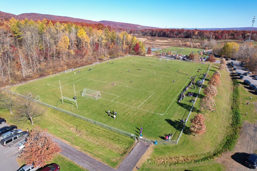 Aerial view of a fall soccer game surrounded by autumn foliage in Northeastern Pennsylvania