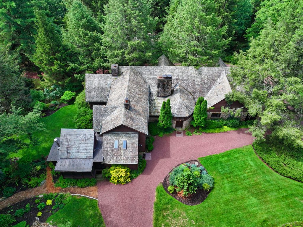 Overhead drone photo of a wooded estate with a curved brick driveway