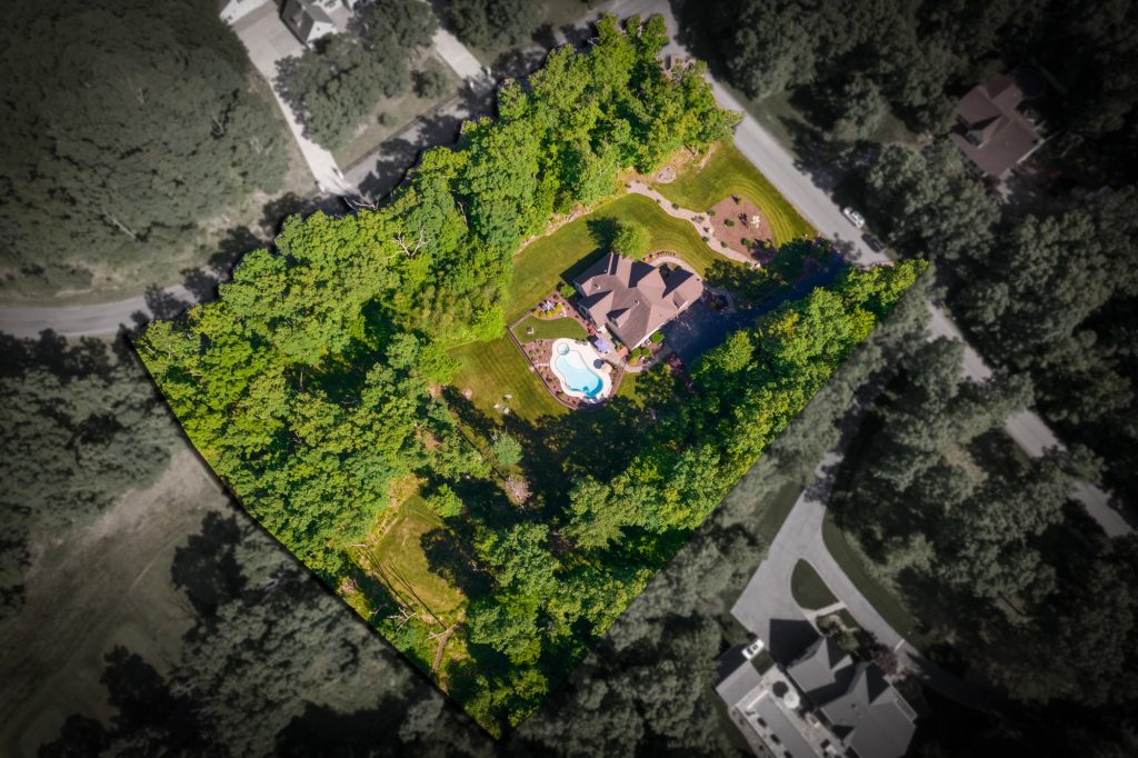 Overhead drone photo of a wooded residential lot with the property lines outlined