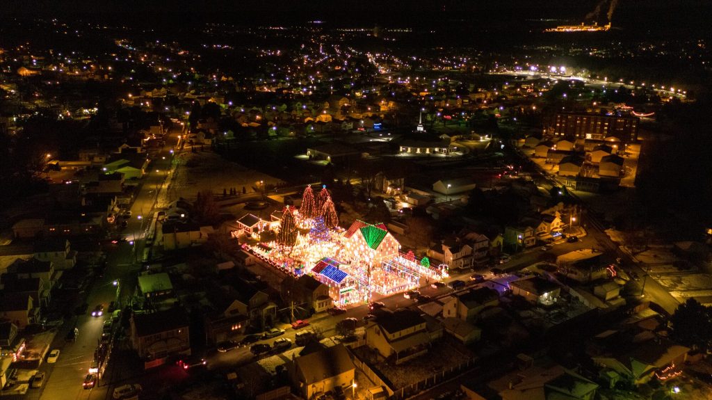 The Peckville Christmas House lit up at night, seen from above with the town around it